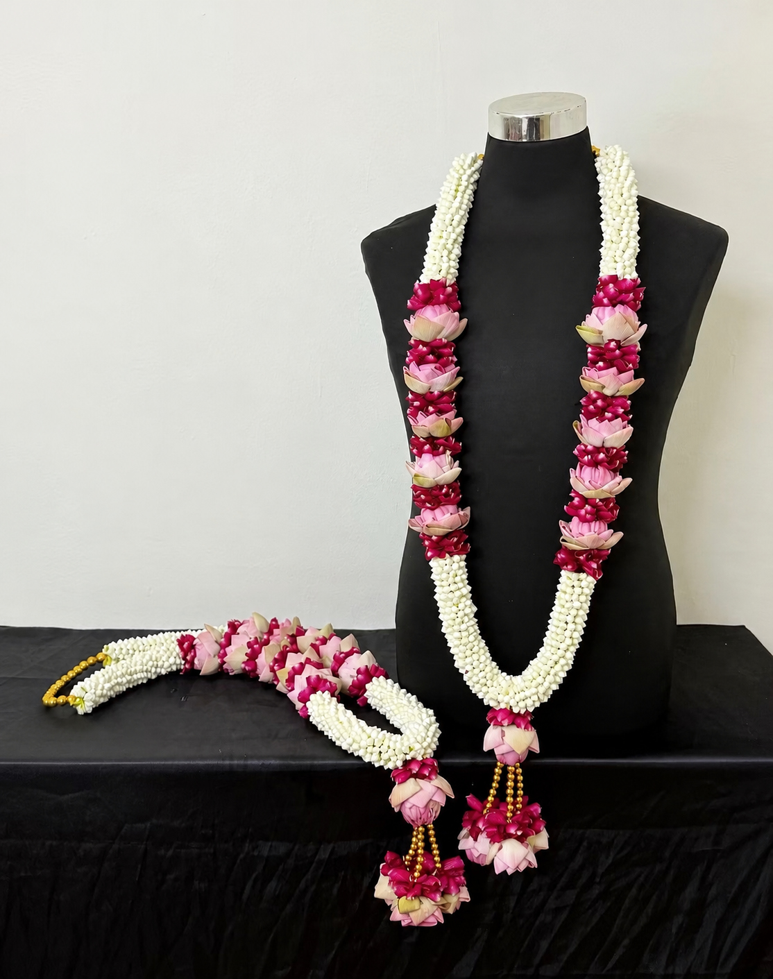 White jasmine, pink lotus, and deep pink wedding garlands on a mannequin, imported from India